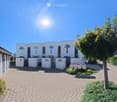 Modern white building with multiple units, numbered entrances, and a paved driveway.