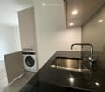 Modern bathroom with a dark granite countertop, stainless steel sink, and a built-in washing machine in a cabinet.