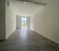 Empty hallway with tiled floor, white walls, and a large sliding glass door leading to an outdoor area.