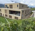 Modern two-story house with large windows, a balcony, and a well-maintained garden.
