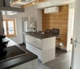 Modern kitchen with white cabinets, dark countertops, stainless steel appliances, and bar stools at the island.