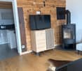 Living room with wooden walls, hardwood floor, television on a wooden cabinet, fireplace, and a cowhide rug.