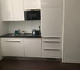Modern kitchen with white cabinets, stainless steel sink, oven, and countertop items including a bottle and brush.
