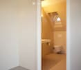Modern, compact bathroom with a sink and toilet, featuring a skylight window for natural light and a sleek, minimalist design.