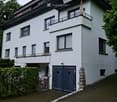 Two-story white house with multiple windows, a garage, and a small balcony on the upper level.