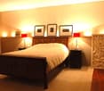 Cozy bedroom with a wooden bed, nightstands, lamps, and picture frames on the wall.