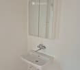 Modern bathroom with a white sink, chrome faucet, and mirrored cabinet.