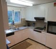 Modern kitchen with white cabinets, granite countertops, stainless steel appliances, and a window overlooking greenery.