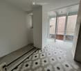 Hallway with hexagonal tile flooring, leading to a balcony area with glass doors and a view of a tiled roof.
