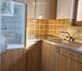 Kitchen with wooden cabinets, a stainless steel sink, and a refrigerator. The backsplash features a patterned tile design.