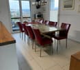 Modern dining room with a glass table, red leather chairs, microwave, and large windows offering a scenic view.