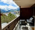 wooden railings, wooden floor, white tiled floor, two lounge chairs with cushions, view of mountains