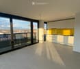 Modern, minimalist kitchen with white cabinets, a yellow backsplash, and a large window offering a city view. The space is clean and well-lit with natural light.