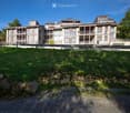 A multi-story residential building with balconies and a surrounding lawn area.