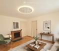 Modern living room with hardwood floors, fireplace, sofa, coffee table, armchair, side table, and decorative items.