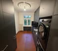 Corridor with dark cabinets, a washing machine, and a window showing greenery outside.
