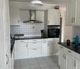 Modern kitchen with white cabinets, stainless steel appliances, and a black countertop.