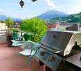 Balcony with a grill, table, chairs, and a scenic mountain view.