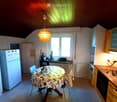 Bright kitchen with wooden cabinets, a dining table with chairs, a refrigerator, and various appliances including a toaster and a sink.
