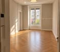 Empty room with wooden herringbone flooring, large window with view, and recessed lighting fixture.