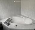 Modern bathtub with sleek chrome faucet and matching trim, set in a tiled corner with grey marble tiles.