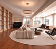 Modern living room with large windows, a sectional sofa, coffee table, chairs, piano, bookshelf, and a round rug.