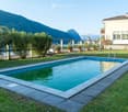 Outdoor garden area with a swimming pool, surrounded by green grass, potted plants, and a scenic mountain view in the background.