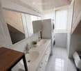 Modern bathroom with double sink, large mirror, washing machine, and potted plant on the counter.