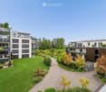 Modern residential complex with multiple apartment buildings, balconies, and landscaped gardens.