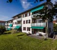 Three story apartment building, green awnings, balconies, green lawn