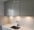 Modern kitchen with marble countertops, stainless steel sink, and sleek grey cabinets.