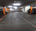 underground parking area with multiple cars parked, orange poles separating spaces