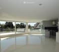 Bright, open-plan living and dining area with large glass sliding doors leading to a balcony, modern kitchen area with cabinets and island, polished tile flooring, recessed lighting.