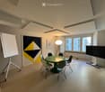 modern office room with a green table, chairs, whiteboard, lamp, TV, radiator, windows