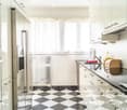 Modern kitchen with stainless steel appliances, white cabinets, and a black and white checkered floor. Features include a refrigerator, oven, microwave, sink, and a dish rack.