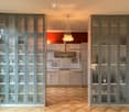 Modern kitchen with grey cabinets, glass-fronted display cabinets, pendant light, and range hood.