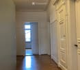 Empty hallway with wooden flooring, white walls, and doors leading to other rooms.