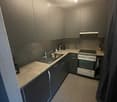 Modern kitchen with grey cabinets, stainless steel appliances, and a tiled floor.