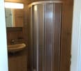 Bathroom with a corner shower stall, a sink with a mirror above it, and a small cabinet below the sink.