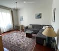 Modern living room with a grey sectional sofa, glass coffee table, floor lamp, side table, and artwork on the walls.