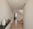 Modern hallway with wooden flooring, white walls, and a staircase leading upwards. Features a small black console table with decorative items, a potted plant, and a white cabinet.