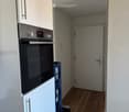 Modern kitchen with white cabinets, stainless steel oven, and wooden flooring.