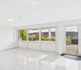 Bright, empty room with white walls, marble flooring, large windows, and a sliding glass door leading to an outdoor area.