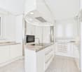Modern white kitchen with granite countertops, stainless steel appliances, and ample cabinetry.