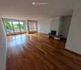 Empty room with wooden flooring, large windows, and a fireplace with a bench.