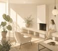 Modern living room with a fireplace, white sofa, coffee table, and potted plants. Natural light streams in from large windows.