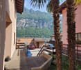 Balcony overlooking a scenic mountain view with palm trees, parked cars, and neighboring houses.