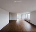 Empty room with wooden flooring, white walls, and large windows allowing natural light. No furniture or equipment present.