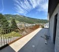 Balcony with tiled floor, wooden railing, and scenic mountain and town view.