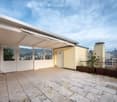 Roof terrace with tiled flooring, covered section, glass railings, and scenic view of the valley and cityscape.